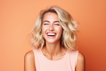 Portrait of a happy young woman laughing, over orange background.
