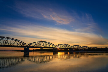 Railway bridge across the river in the background of the sunset