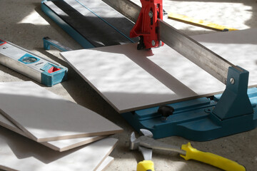 Cutingt tiles with a standard manual tile cutter. Process of installation of tiles in the bathroom step by step. DIY home improvement.	