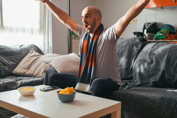 Young man celebrating while watching sports on the sofa