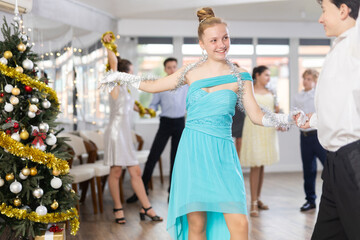 Teenagers in holiday clothes dancing swing dance near the Christmas tree