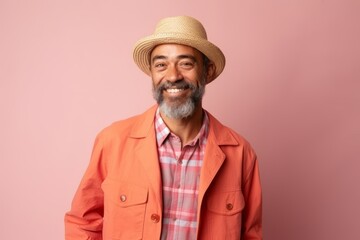 Portrait of a happy senior man with hat and coat over pink background