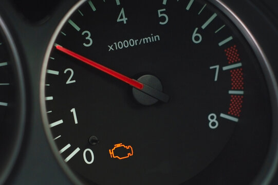A close-up view of a car's tachometer with the check engine warning light illuminated, indicating a potential issue with the vehicle's performance or emissions system.