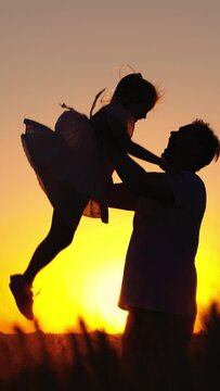 Child dad play superhero, fly sky. Dad plays with his daughter, throws child up into sky with his hands, happy child. Family game. Father, child, little girl having fun together in park against of sun