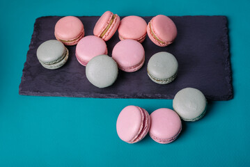 Close up colorful macarons dessert with vintage pastel tones on black stone board.