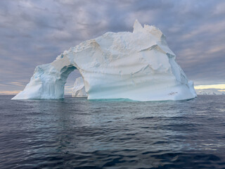 A huge high breakaway glacier drifts in the southern ocean off the coast of Antarctica at sunset,...