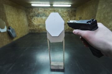 Tactical pistol shooting at a paper target at a shooting range.