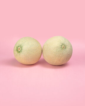 Two Equal Melons with Different Alignment on Pink Background, Uneven Woman Breasts Concept