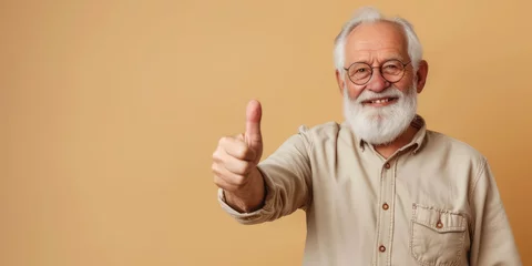 Fotobehang smiling elderly gray-haired man in glasses shows thumbs up on a colored background in the studio, pensioner, old age, grandfather, portrait of a mature person, beard, casual wear, gesture, happy © Julia Zarubina