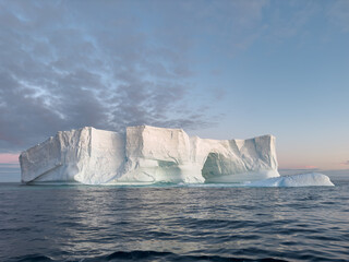 A huge high breakaway glacier drifts in the southern ocean off the coast of Antarctica at sunset,...