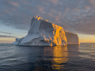 A huge high breakaway glacier drifts in the southern ocean off the coast of Antarctica at sunset,...