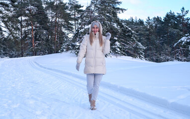Fototapeta na wymiar A woman in a white jacket and hat standing in the snow.