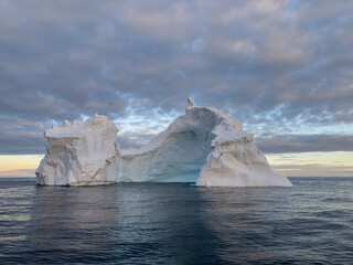 A huge high breakaway glacier drifts in the southern ocean off the coast of Antarctica at sunset,...
