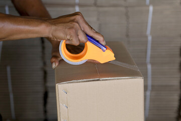 workers seal carton boxes with plastic tape or sealtape in the process of packaging products for...