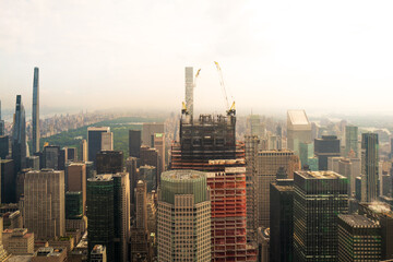 New York City, USA, a hazy polluted low mist engulfs the sky. Looking down on skyscrapers. New skyscraper is being built with Central Park in the background