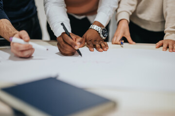 Multiracial team analyzing reports, brainstorming strategies for business growth in a late-night office work session. Focused executives collaborating to meet project deadline.