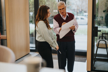 Senior executive reviewing documents with young female colleague in office.