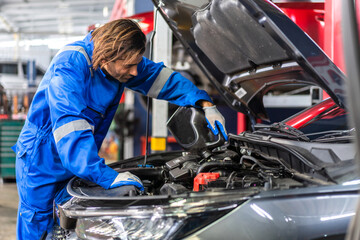 Car technician mechanic man in uniform work fixing vehicle car engine and maintenance repairing...