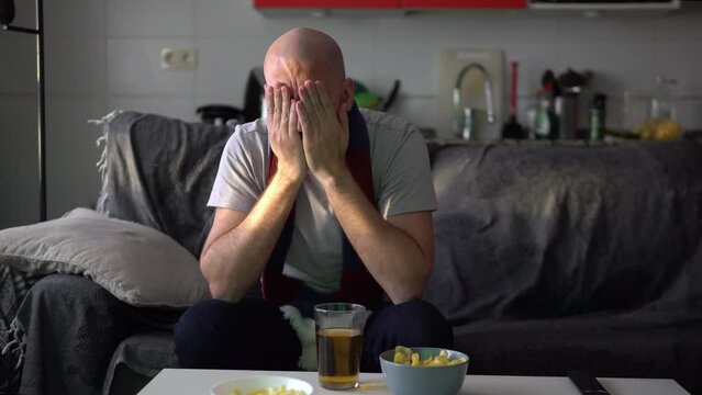 Defeated young man watching sports on the sofa
