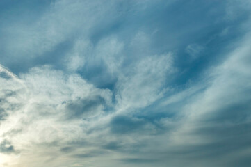Fototapeta premium A serene sky painted with soft blue tones and delicate wisps of clouds captures the tranquil transition of day to dusk.