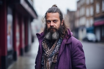 Portrait of a handsome long-haired bearded man in a purple coat.