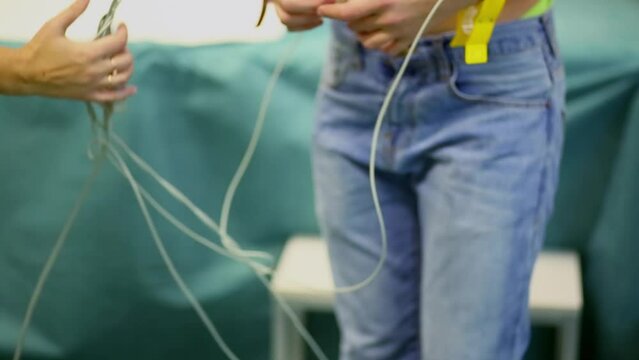 Child in jeans stands with wires stick to his body in medical cabinet