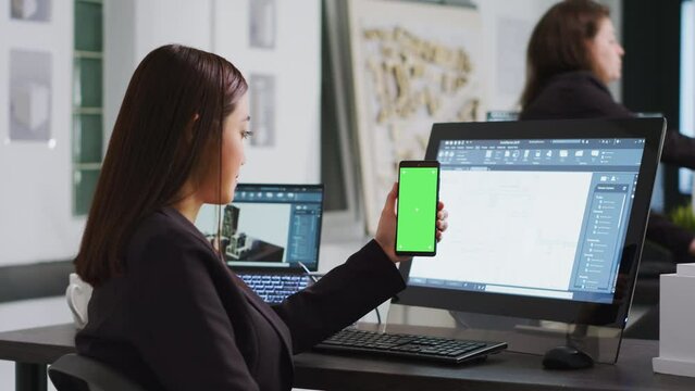 Engineer showing phone with greenscreen template on display, working at a architectural agency office. CAD expert using isolated chromakey layout on copyspace screen, mockup concept.