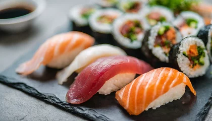 Selbstklebende Fototapeten sushi set, featuring assorted sashimi and sushi rolls elegantly arranged on a sleek stone slate, epitomizing culinary artistry and Japanese gastronomic delight © Your Hand Please