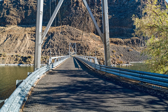 A one-lane suspension bridge spans across the Deschutes River at Cove Palisades State Park, Oregon, USA