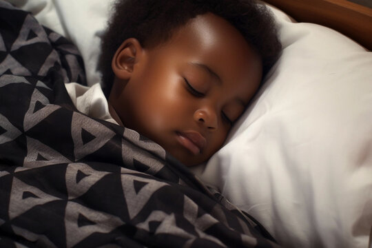 Little boy, Afro-american child, with black skin, sleeping in bed with closed eyes under the blanket.
