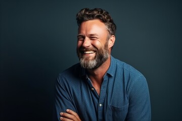 Portrait of a handsome mature man laughing against dark blue background.