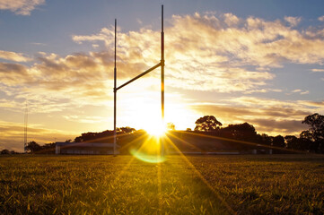 Goal posts for the sports of rugby league or rugby union football on the field at sunset  - 722608782