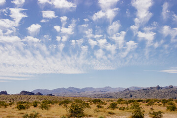 Beautiful blue sky with fluffy clouds over a desert with mountains in Arizona, USA. Panorama with high hills. Landscape on a sunny day