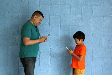 Divorced single dad with 9-year-old son, dark-skinned Latinos use their cell phone, ignore each other and get upset for not paying attention - obrazy, fototapety, plakaty