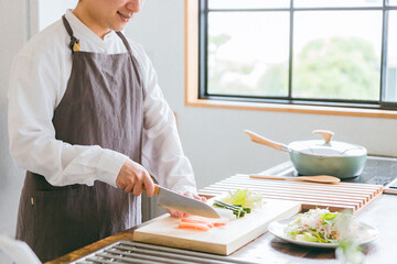 キッチンに立ち野菜を着る男性（料理・料理男子・包丁・切る）
