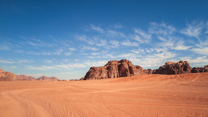 Wadi Rum, Jordan, Scenic view of Arabic Middle Eastern desert against clear blue sky with sand tracks in foreground. Mountain in background. Copy space no people - obrazy, fototapety, plakaty