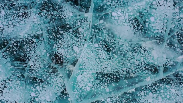 Aerial drone view frozen methane bubbles and cracks in the ice on Lake Baikal Siberia Russia. Natural cold background of ice. Winter abstract background. High quality 4k footage