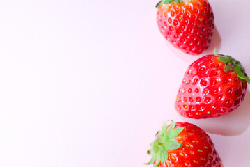 右に3つ並んだ赤いいちご　ピンク色の背景　春のフルーツ