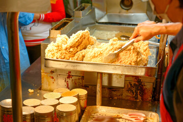 A stall vendor seasoning crispy deep-fried chicken cutlets with spice & salt, one of local people's favorite street-foods, in Raohe Street Night Market, Taipei, where traditional snacks can be savored
