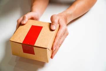 cardboard box with a red,Man's hand holding a cardboard box with a red sign,Isolated on Grey studio Background. Copy Space.