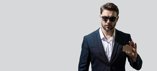 Business man holding credit card over isolated studio gray background. Businessman with credit bank card, recommend bank or shopping discounts. Banner for header, copy space. Poster for web design.