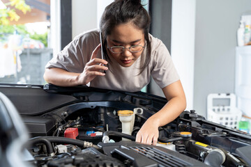 A woman mechanic performs engine maintenance on a car in an auto repair garage, using tools to change the engine and provide essential automotive service