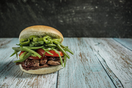 Chacarero, sandwich with chili, green beans, meat, and tomato on wooden table. Copy space. Typical Chilean cuisine