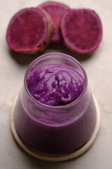 Obraz na płótnie Canvas Ipomoea batatas. purple sweet potato smoothie in clear glass. a healthy diet containing lots of antioxidants and a source of carbohydrates.