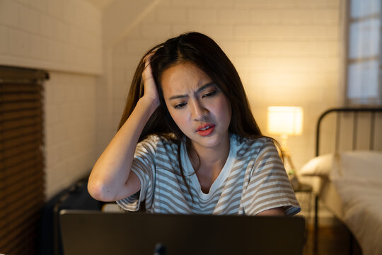 A very stressed Asian businesswoman working from home takes off her glasses feeling eye strain and fatigue from her laptop computer a tired Asian freelancer is suffering from headaches, At home.