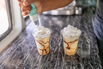 Barista covering a frappe with cream on top