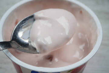 spoon picks fresh yogurt in a plastic container 