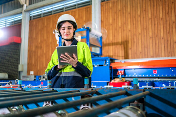 Fototapeta na wymiar Professional machanic engineer technician industrial woman wearing safety uniform working control with tablet on heavy machine in manufacturing factory production line.business technology robot