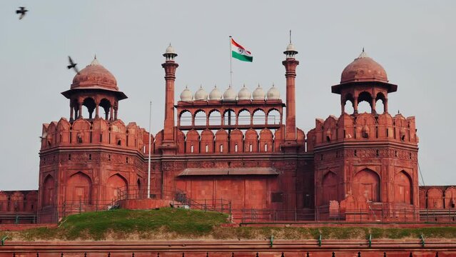 birds flying in front of red fort with swaying indian flag at delhi, india. stable shot 4k