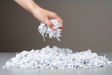 Hand holding a bunch of shredded paper against gray background